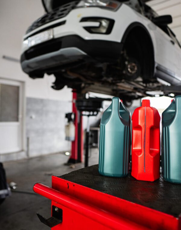 Car maintenance in garage with motor oil bottles in foreground A garage scene showing american car on a lift with motor oil bottles in the foreground. Perfect for depicting automotive maintenance or repair settings.